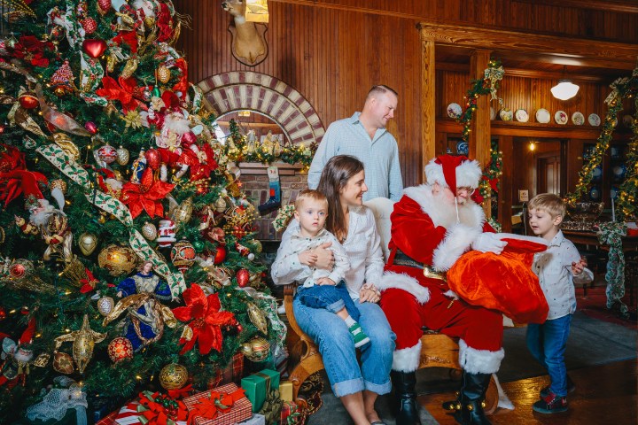 Family with Santa Claus next to a decorated Christmas tree.